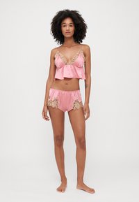 Set di lingerie in satin rosa con dettagli in pizzo, composto da un bralette arricciato e pantaloni abbinati con dettagli in pizzo floreale sui lati.