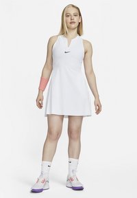 Valge tennisekleit ilma varrukateta ja kraega, millel on must Nike'i logo. Kandis roosat randmevalgatust ja valgeid jalatseid lilla aktsentidega.