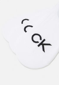 Meias brancas até ao tornozelo com logótipo bordado em preto. Material de algodão suave, design de bico redondo e altura discreta para uso discreto.