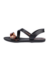 Sandalias planas negras con detalles de estampado de leopardo en la tira. Presentan una suela texturizada y un diseño entrecruzado. Fabricadas con un material flexible.