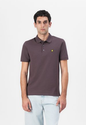 Mörklila polo-shirt i bomull, med klassisk krage, korta ärmar och en gul broderad logotyp på bröstet.