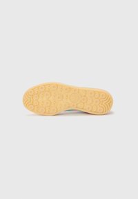 Semelle de chaussure en caoutchouc orange clair avec des motifs de bande de roulement circulaires et une zone d'arche texturée. Présente un logo au centre.