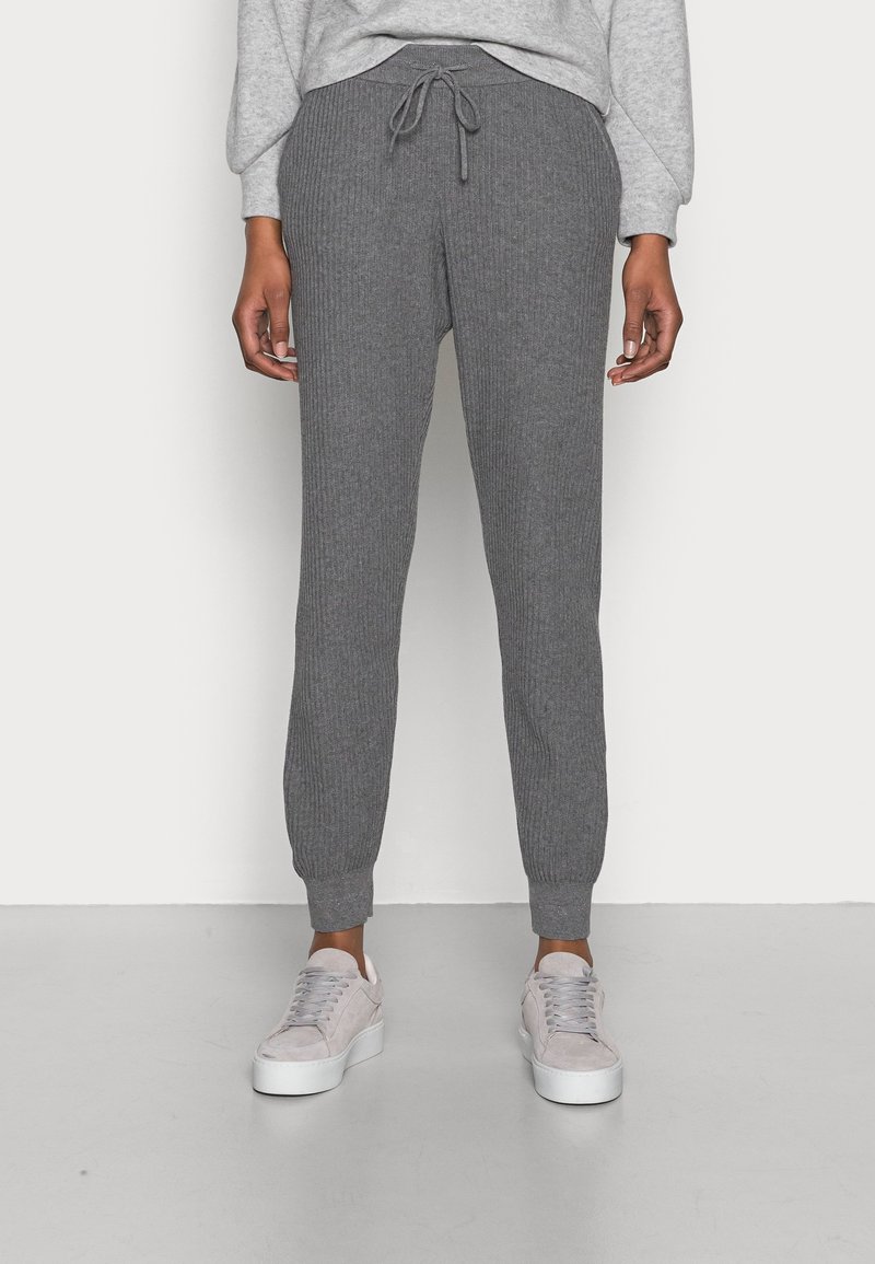 Grijze geribbelde joggers met een elastische tailleband, trekkoord en taps toelopende boorden, gecombineerd met lichtgrijze sneakers.
