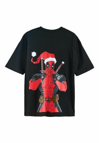 T-shirt en coton noir avec un graphisme rouge de Deadpool portant un chapeau de Père Noël, tenant deux katanas, avec des accents de couleur et un design de style cartoon.