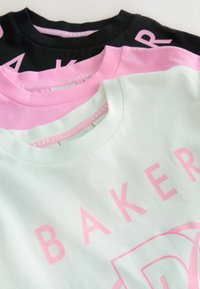 Kolme t-paitaa pinottuna: yksi musta, yksi vaaleanpunainen ja yksi mintunvihreä, jokaisessa suuri 'BAKER'-logo kontrastiväreissä. Puuvillamateriaalia, lyhyet hihat.