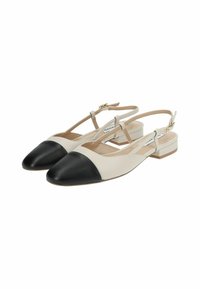 Beige slingback-sko med svart lær spiss tå, med flat hel, justerbar stropp og glatt tekstur.