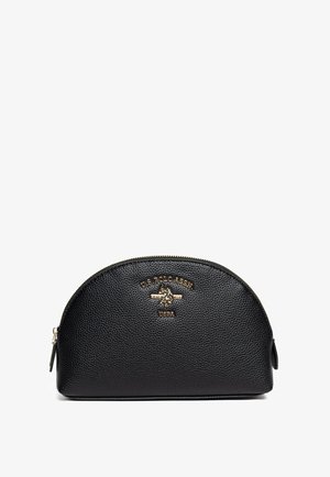 Zwarte lederen cosmeticatasje met een afgeronde vorm, gestructureerd oppervlak, gouden hardware-detail en geperst logo aan de voorkant. Zijritssluiting.