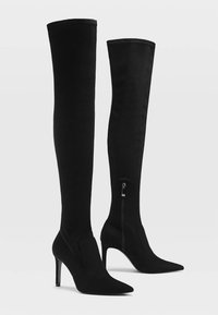 Knee-high black fabric boots with a pointed toe, stiletto heel, and a side zipper detail. Smooth texture and fitted design.