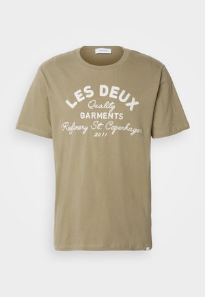 T-shirt de algodão verde oliva com gola redonda, apresentando texto branco: "LES DEUX Quality Garments Refinery St. Copenhagen 2011." Textura suave.