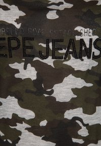 Tričko s maskáčovým potiskem v odstínech zelené a šedé s logem "Pepe Jeans" posetým černými kamínky na hrudi. Měkká bavlněná tkanina.
