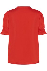 Blusa rossa con maniche corte a sbuffo con dettagli arricciati, una texture liscia e un orlo arrotondato. Design semplice a tinta unita.