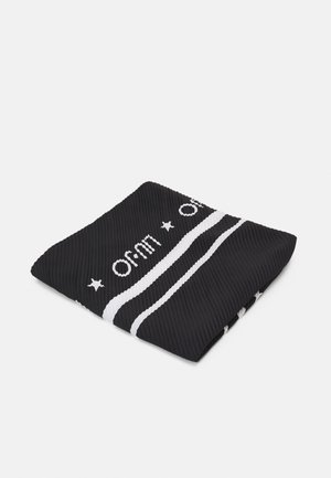 Tissu noir côtelé plié avec deux bandes blanches horizontales et texte blanc ainsi que des étoiles partiellement visibles sur un fond uni.