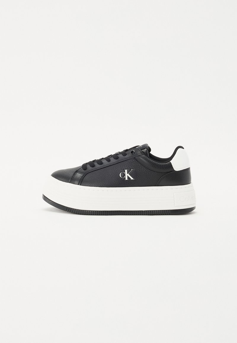 Fekete és fehér platform sneaker, texturált felsőrésszel, kerek orral, fűzős záródással és egy feltűnő logóval az oldalon. Gumi talp.