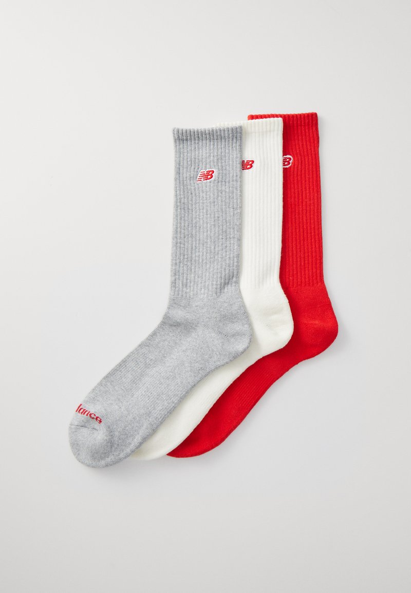 Tre par ribbade strumpor i grått, vitt och rött, med små New Balance-logotyper i rött på grå och vita strumpor, och vita på röda.