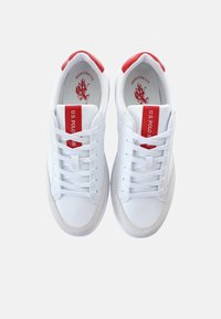 Sneakers bianchi con una finitura in pelle liscia, dettagli rossi sul tallone e sulla linguetta, e lacci. Presentano il logo sulla linguetta e cuciture laterali.