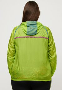 Grön lättviktig jacka med huva, med en blå accent vid halslinningen och lila branding över ryggen, texturerad tyg.