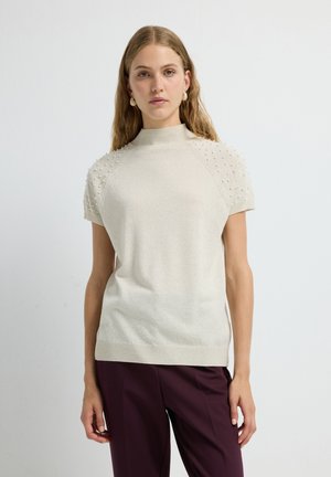 Maglione a maniche corte lavorato a maglia in beige chiaro, con un collo alto e dettagli a nuvola testurizzati sulle spalle. Finitura del tessuto liscia.