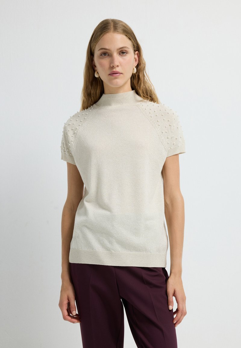 Gebreid sweater met korte mouwen in lichtbeige, met een hoge halslijn en getextureerde pofdetails op de schouders. Gladde stoffenafwerking.