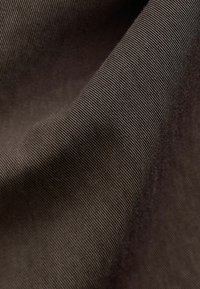Tejido marrón texturizado con un sutil tejido diagonal, que muestra finas líneas y una superficie suave y lisa. Adecuado para diversas aplicaciones textiles.