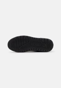 Svart sneaker såle med teksturert gummi og et mønstrete dekk for grep. Fremtredende merkevare på siden og en buet hæl.