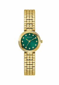 Reloj de pulsera en tono dorado con una esfera redonda verde, decorada con strass. La correa presenta un diseño flexible y texturizado. Nombre de la marca visible.