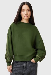 Grön oversized sweatshirt med rund halsringning, långa ärmar och dragkedjedetaljer på ärmarna. Tillverkad av mjukt tyg med en slät textur.