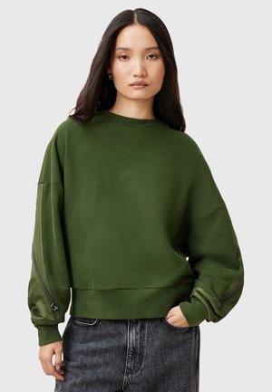 Zielony oversize sweter z okrągłym dekoltem, długimi rękawami i zamkami błyskawicznymi na rękawach. Wykonany z miękkiego materiału o gładkiej teksturze.