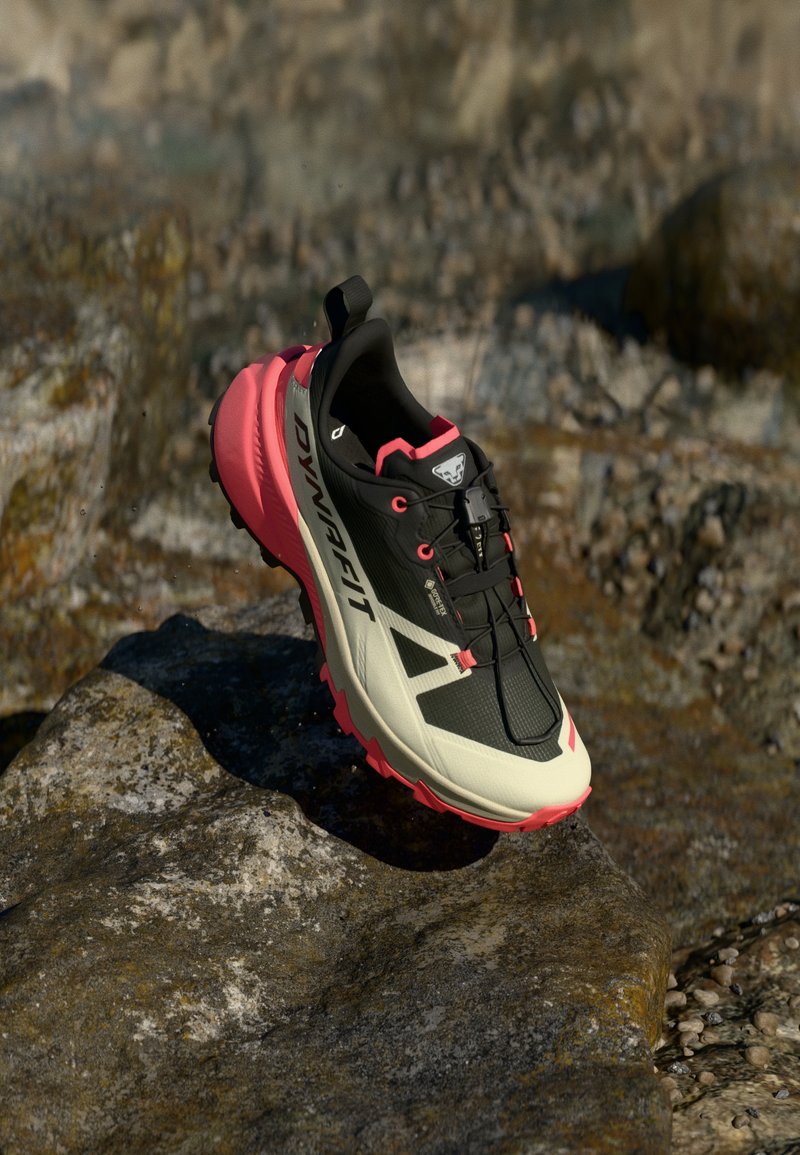 Παπούτσι trail running με μαύρο άνω μέρος και ροζ λεπτομέρειες, υφή επιφανειών, ελαφρύ σχεδιασμό και επενδεδυμένη ροζ σόλα.