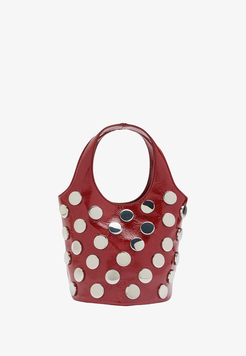 Czerwona, błyszcząca torebka z sztucznej skóry, ozdobiona okrągłymi, srebrnymi ćwiekami ułożonymi w wzór. Zaokrąglony górny rant z krótkimi uchwytami.