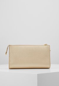 Prostokątna torebka kopertowa ze złotej skóry o fakturowanej powierzchni oraz złotym akcentem w postaci suwaka. Posiada minimalistyczny design, bez widocznych logotypów czy wzorów.