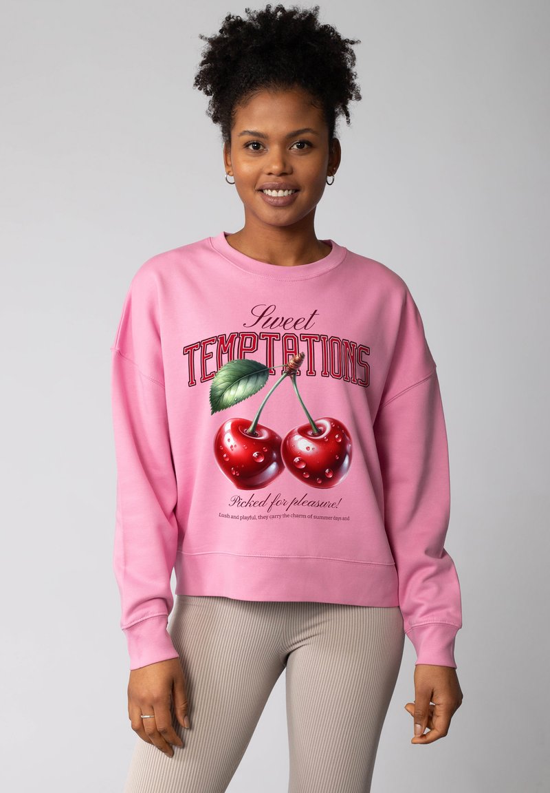 Rosa Sweatshirt mit Rundhalsausschnitt, großem Kirschenmotiv und dem Schriftzug "Sweet Temptations." Gerippte Bündchen und Saum, weiche Stoffstruktur.