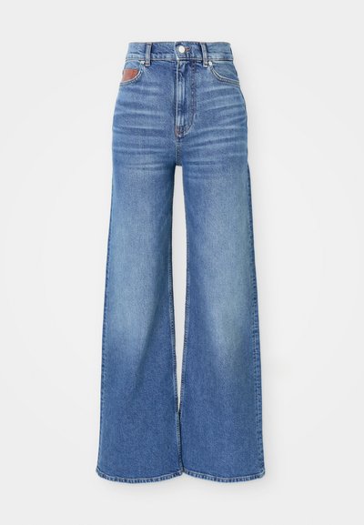 Jeans de pierna ancha de cintura alta en denim azul claro con un ligero desvanecimiento, que presentan un cierre de botón y un detalle de cuero en la parte trasera de la cintura.