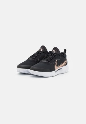 Paire de chaussures de sport noires avec semelles blanches et logo swoosh bronze, affichées côte à côte sur fond blanc.