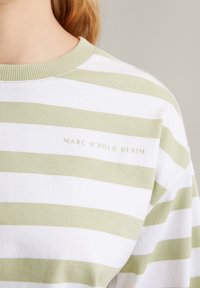 Gestreepte korte mouwen t-shirt in wit en lichtgroen, met een geribbelde ronde halslijn en "MARC O'POLO DENIM" tekst in lichte borduur. 