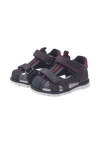 Sandales pour enfants bleu marine avec des coutures rouges, des sangles Velcro réglables et un design ouvert. Présente une semelle blanche avec des détails texturés.