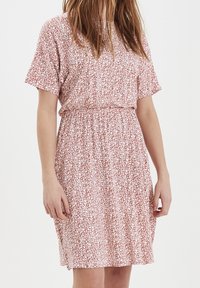 Šaty s krátkým rukávem se vzorem růžových a bílých květin, mají elastický pas a volný střih. Lehká látka s jemnou texturou.