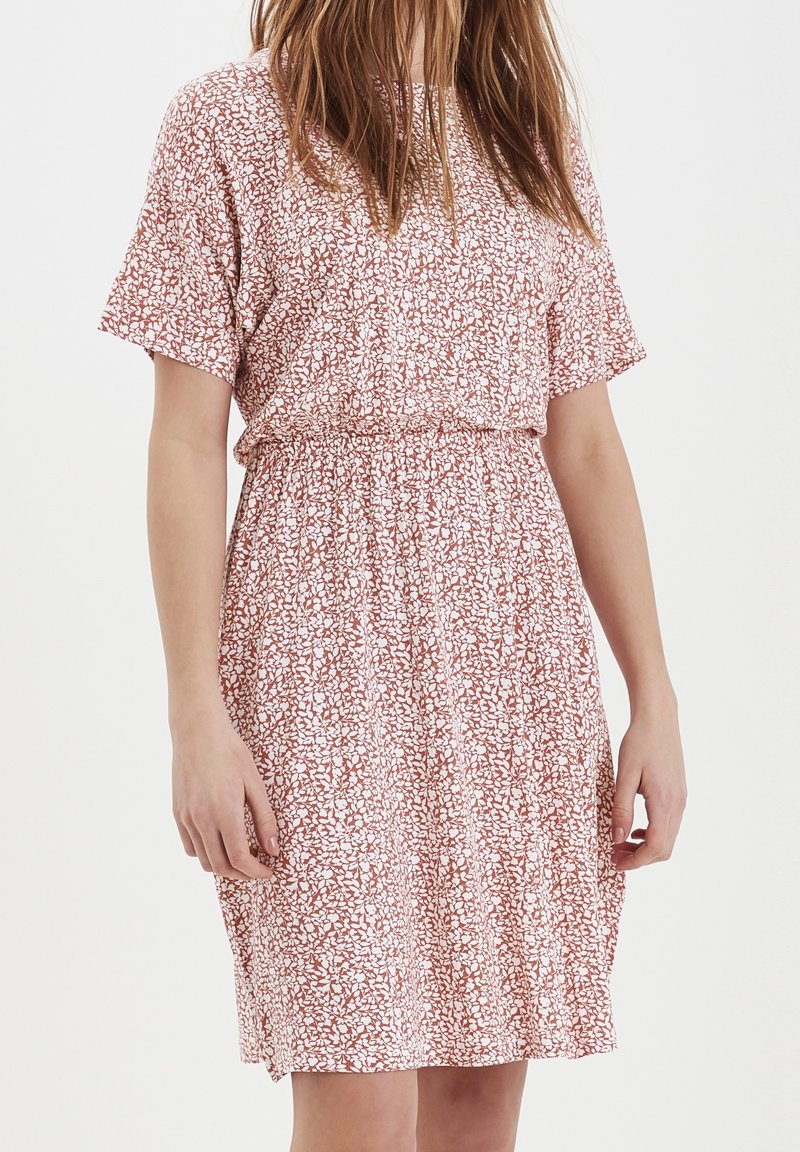 Šaty s krátkým rukávem se vzorem růžových a bílých květin, mají elastický pas a volný střih. Lehká látka s jemnou texturou.