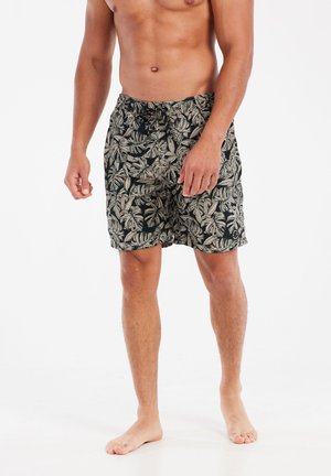 Zwarte zwemshorts met een beige tropisch bladpatroon, elastische tailleband met trekkoord en een lengte boven de knie.