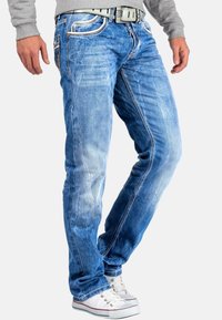 Lichtblauwe denim jeans met een vervaagd ontwerp, contrasterende stiksels, een vijf-pocketstijl en een rechte pijp. Witte sneakers maken de look af.