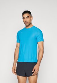 T-shirt atlético azul de manga curta, feito de tecido leve, com um decote redondo e um detalhe de logotipo discreto no ombro.