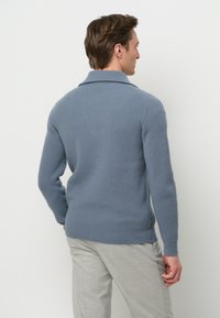Gestreifter blauer Strickpullover mit kragenförmigem Halsausschnitt, langen Ärmeln und einer leicht taillierten Form, von hinten vor einem weißen Hintergrund dargestellt.