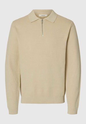 Beige genser med polokrage, har en kort glidelås. Teksturert ribbestrikket stoff og tettsittende mansjetter med ribbestrikket kant nederst.