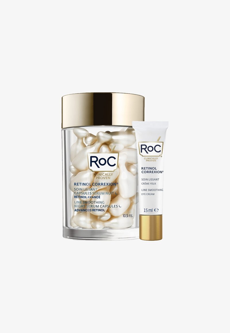 Heldere glazen pot met een gouden deksel, gevuld met crème-gevulde witte capsules. Inclusief een witte tube oogcrème met gouden accenten.