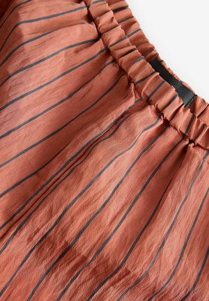 Duga suknja boje hrđe s crnim vertikalnim prugama i skupljenim elastičnim pojasom. Tekstuirani materijal s blagim sjajem.