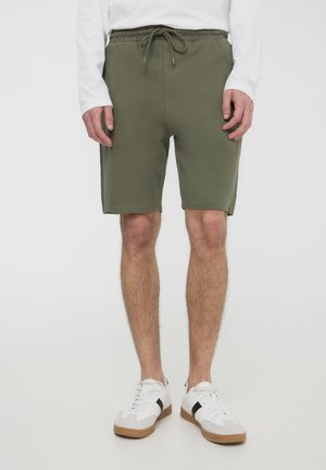 Shorts verde oliva, fino al ginocchio, realizzati in morbido misto cotone. Presentano una vita elastica con cordoncino e tasche laterali.