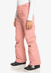 Pantalons de neige roses avec une texture lisse, conçus avec deux boutons à la taille, des poches latérales et des genoux renforcés pour la durabilité.