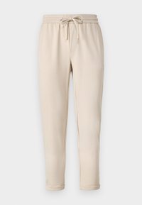 Beige joggerbukser med elastisk talje og snøre, der har sidelommer og tætsiddende ankler. Glat tekstur, casual design.
