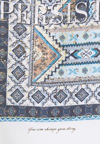 Wzorzysta tkanina z geometrycznymi i kwiatowymi wzorami w odcieniach niebieskiego, kremowego i brzoskwiniowego, z złotymi literami, które informują "WYTRWAŁOŚĆ" ponad cytatem.