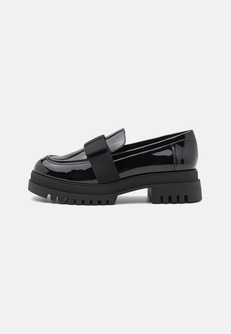 Mocassin en cuir noir brillant avec semelle crantée épaisse et large bande élastique sur le dessus, vu de profil sur un fond uni.