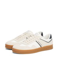 Beige sportcipők, textúrált felsőrésszel, nubuck díszítéssel és fehér bőrpanelekkel. Barna gumitalp és fekete részletek a saroknál.